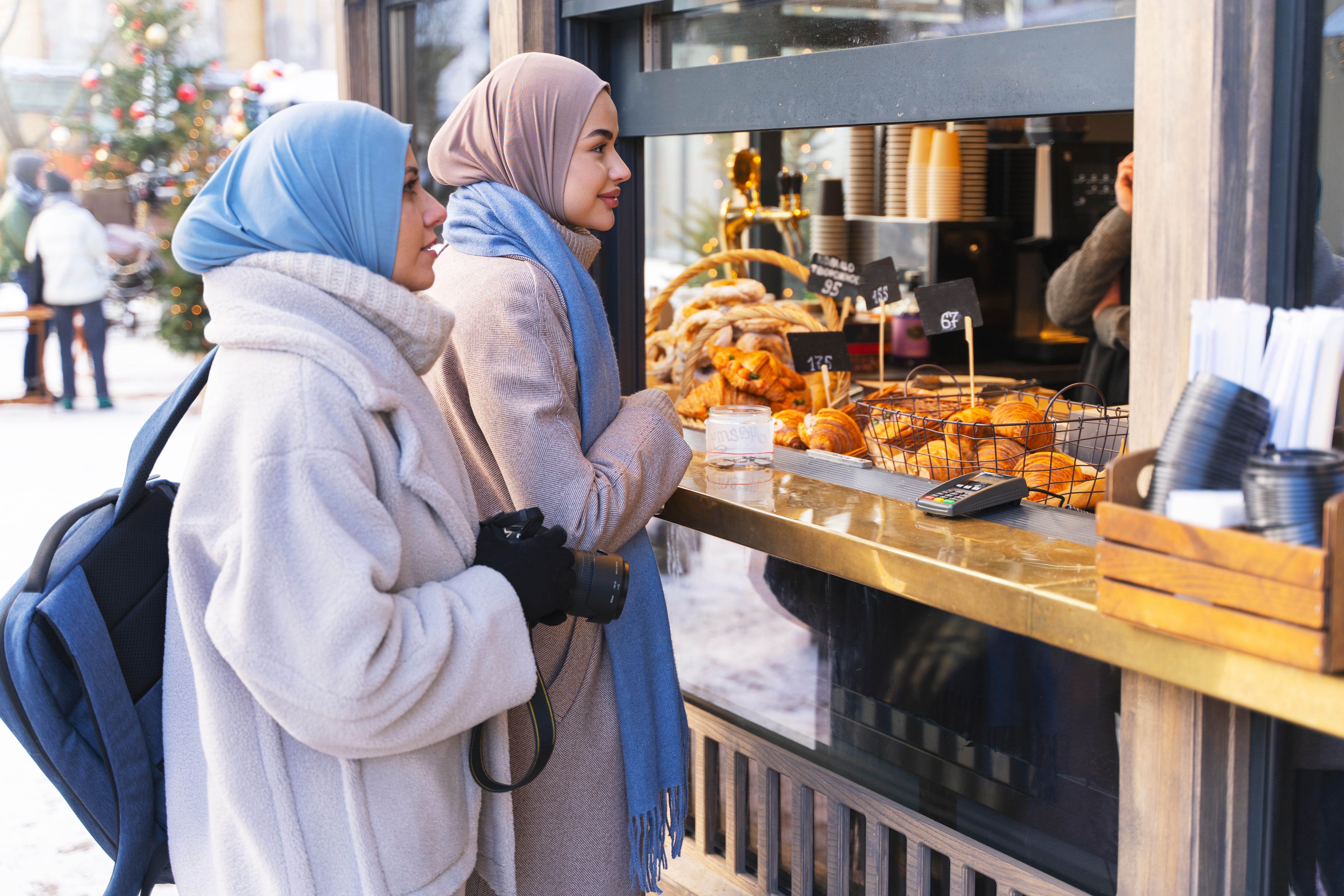 two-muslim-women-buying-food-from-pastry-shop-while-traveling
